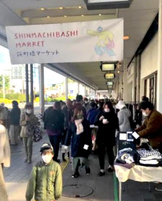 新町橋商店街の歩道でマーケットを開催し、多くの人が通りにいる様子