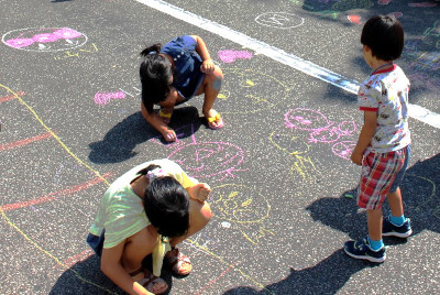 道路で子供たちがチョークでお絵かきしている様子