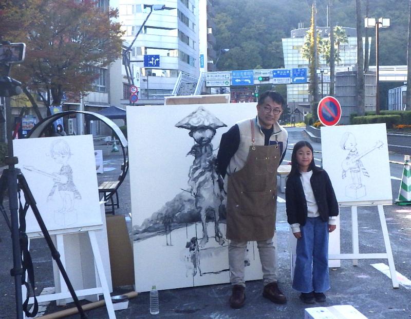 鈴木良治氏のドローイングライブでの作品を背景に、鈴木良治氏とtoa氏