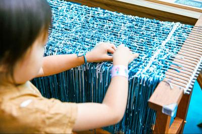 染め上げた糸を奉納という形でゾーン内の織機に結んでいる様子