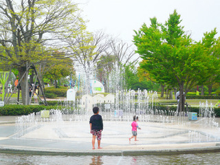 噴水から水が噴き出して子供が中に入って遊んでいる
